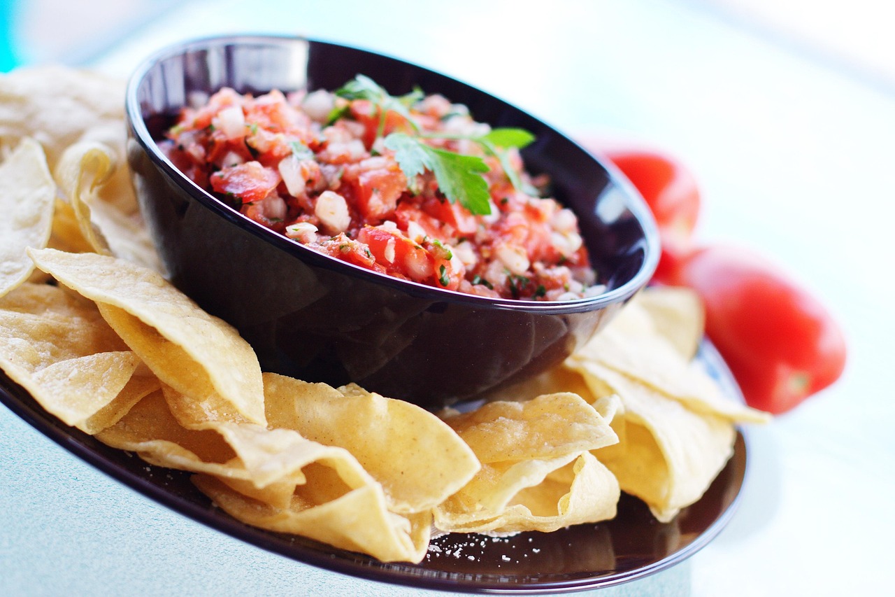 Tortilla chips with fresh tomato salsa in black bowl